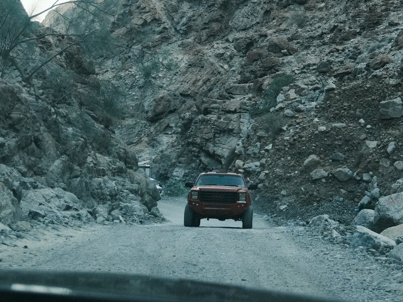 A rugged vehicle navigating a rocky mountain road surrounded by steep cliffs.