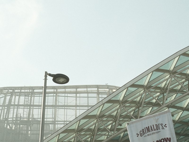 A modern glass building with a street lamp and a banner in front, under a hazy sky.