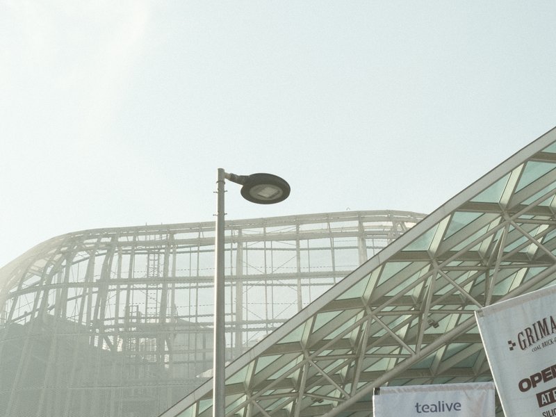 A modern architectural structure with glass and metal elements under a hazy sky.