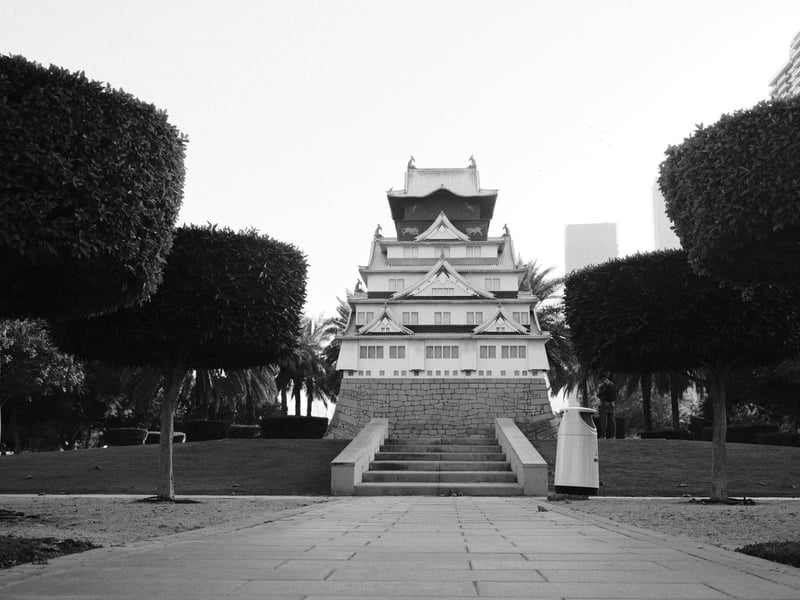 A traditional Asian-style building surrounded by manicured trees in a park setting.