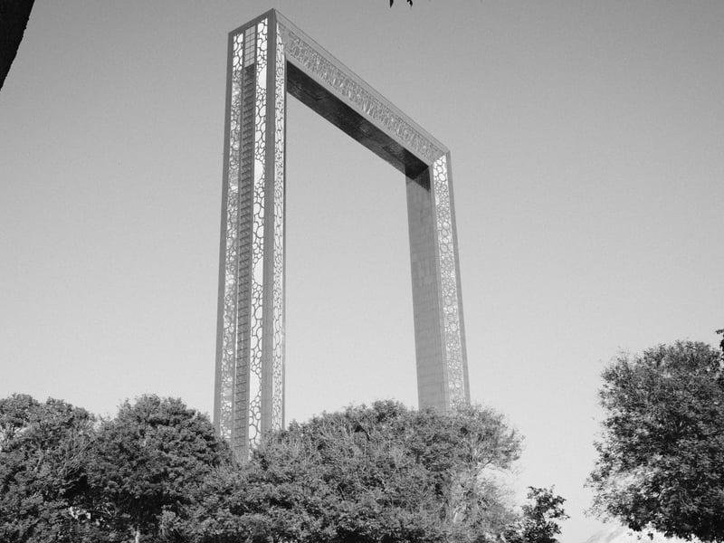 A large rectangular frame structure surrounded by trees against a clear sky.