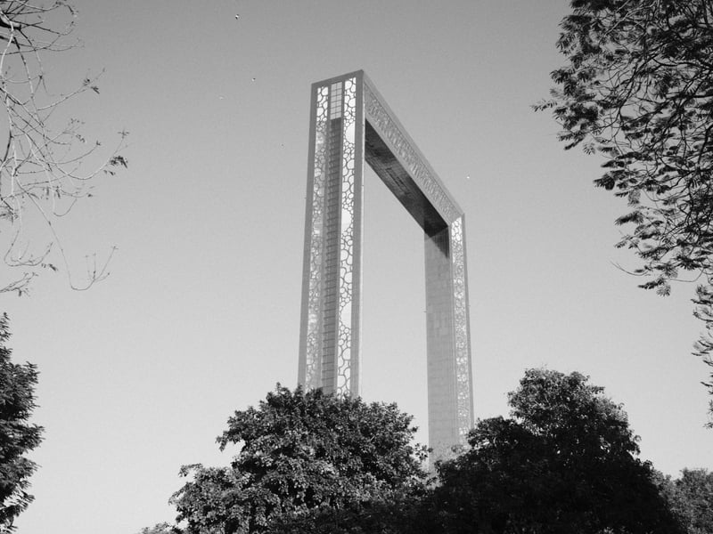 A large rectangular metal structure rising above trees in a black and white photograph.
