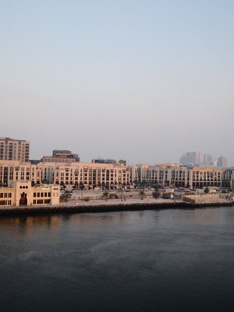 A waterfront view of modern buildings along a calm river during twilight.