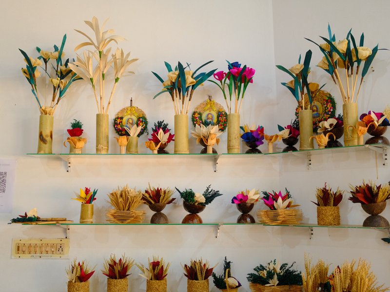 Colorful handmade crafts displayed on shelves, featuring flowers and decorative items made from natural materials.