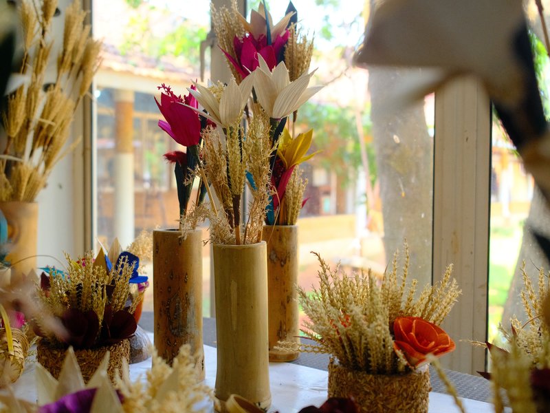 A collection of decorative dried flowers in various vases, arranged on a table near a window.