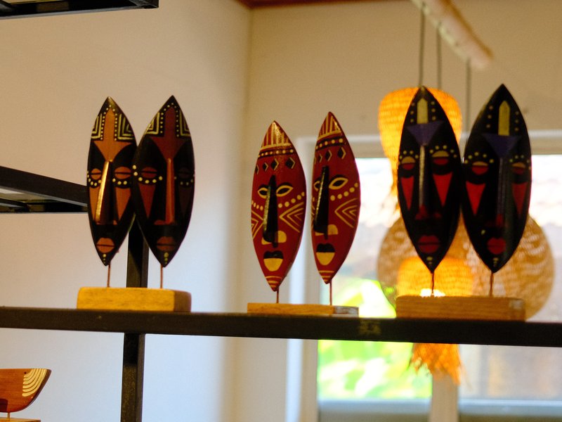 Colorful wooden masks displayed on a shelf in a bright indoor setting.