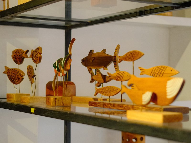 A collection of wooden fish sculptures displayed on a shelf.