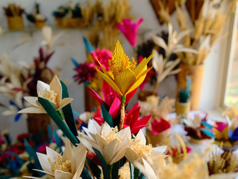 Colorful artificial flowers made from natural materials in a bright indoor setting.