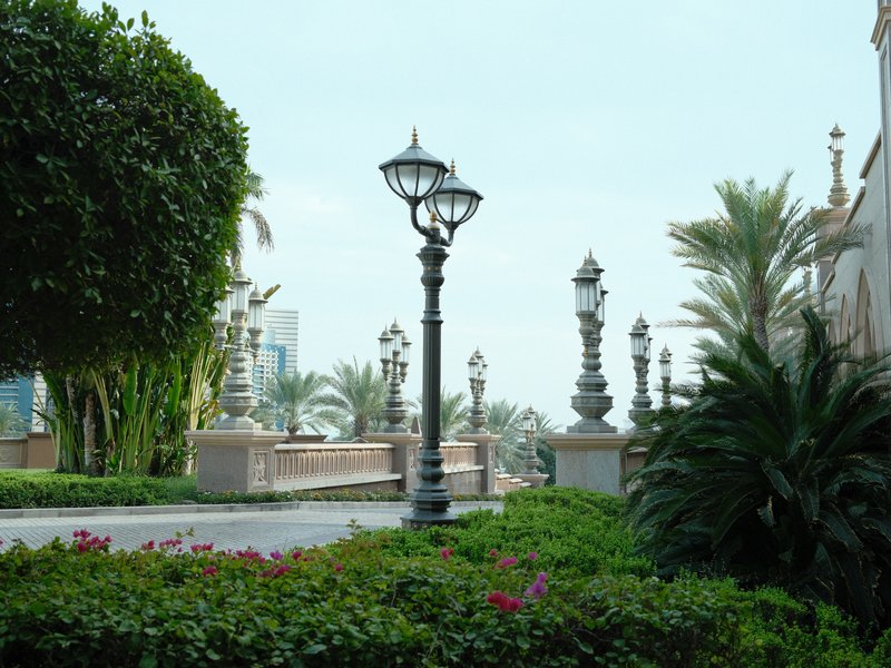 A scenic view of a pathway lined with decorative lampposts and lush greenery.