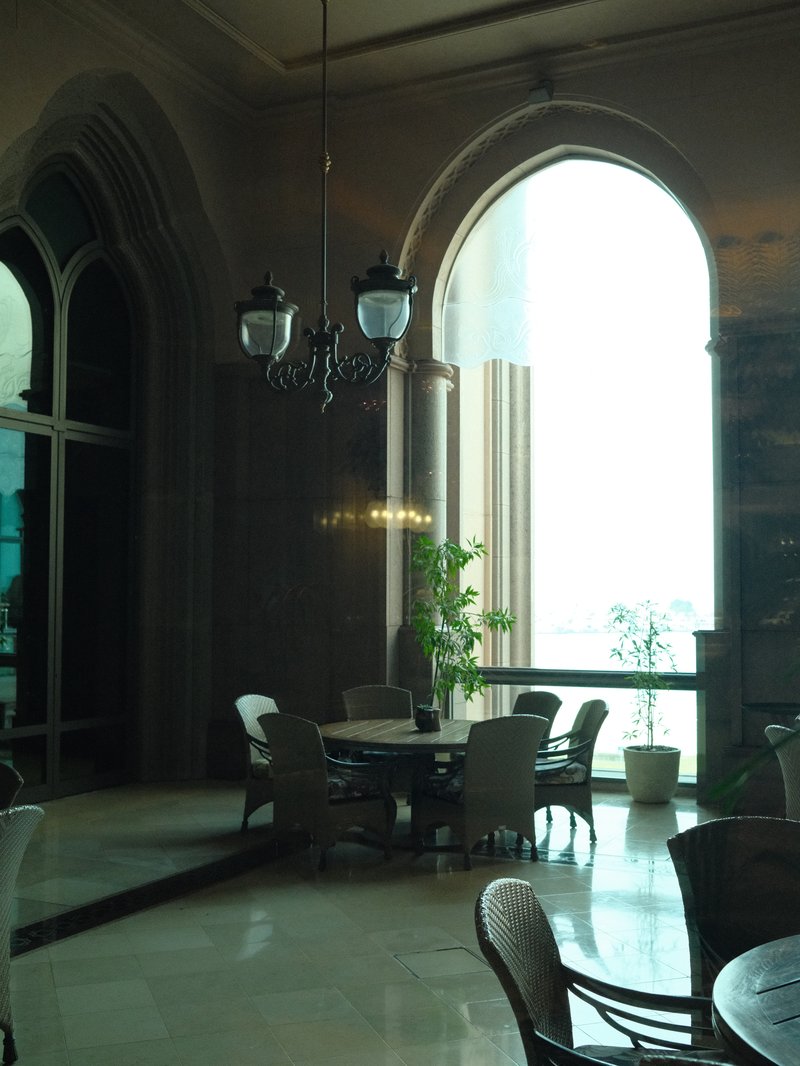 Interior of a stylish dining area with large windows and elegant furnishings.