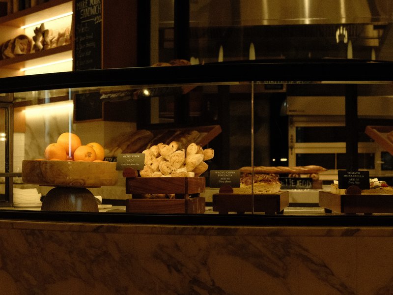 A dimly lit display case filled with various pastries and desserts in a cozy café setting.
