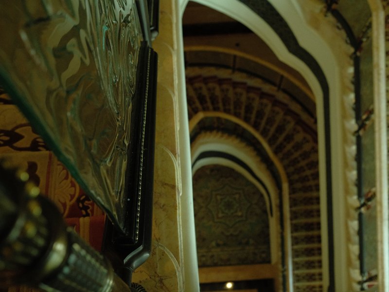 A view of ornate arches in a dimly lit corridor with intricate details and textures.