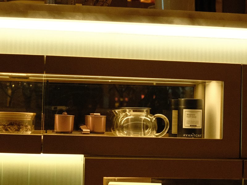 A modern kitchen cabinet with glass doors displaying a glass pitcher and various containers.