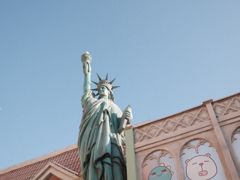 Statue of Liberty replica against a clear blue sky with colorful murals in the background.