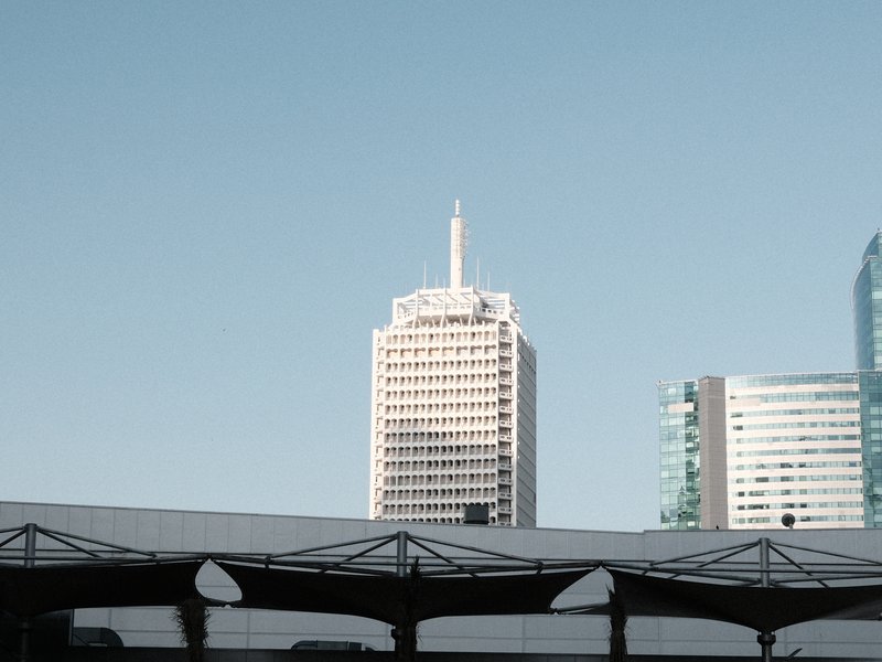 A view of tall buildings against a clear blue sky, with a rooftop structure in the foreground.