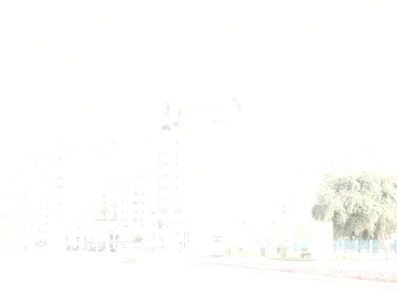 A bright, overexposed scene featuring buildings and trees in a city.