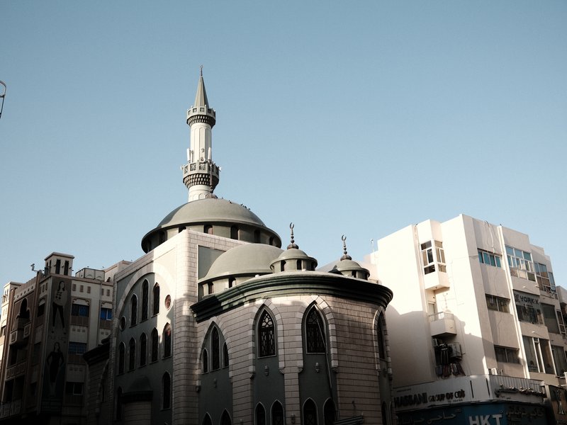 Historic building with a mosque tower against a clear blue sky in an urban setting.