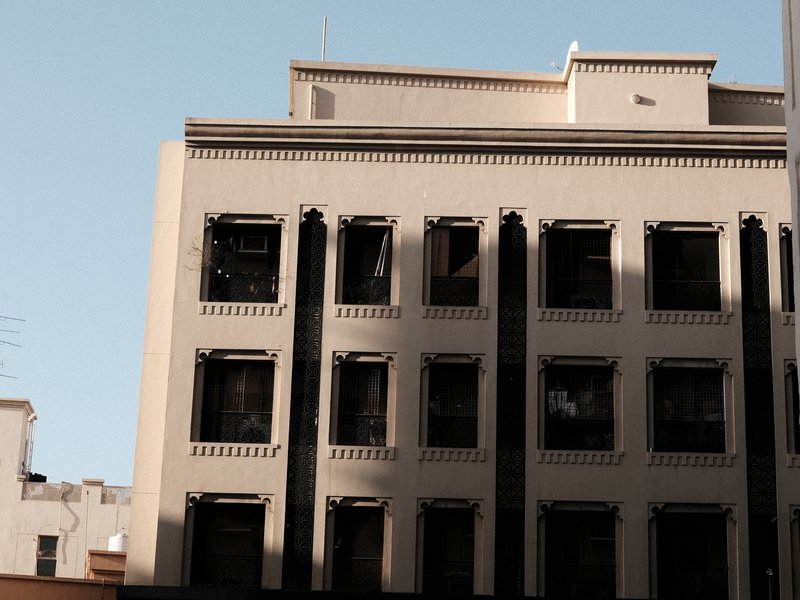 A close-up view of a historic building with architectural details and shadows cast on its facade.
