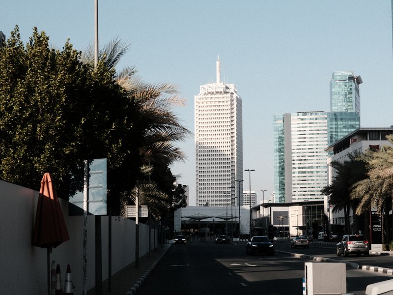Urban scene featuring tall buildings and palm trees under a clear sky.