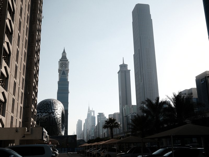 City skyline featuring tall buildings and a unique spherical structure under bright sunlight.