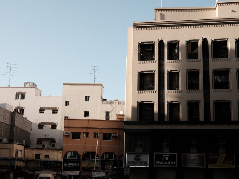 A cityscape featuring buildings with varying architectural styles under a clear blue sky.