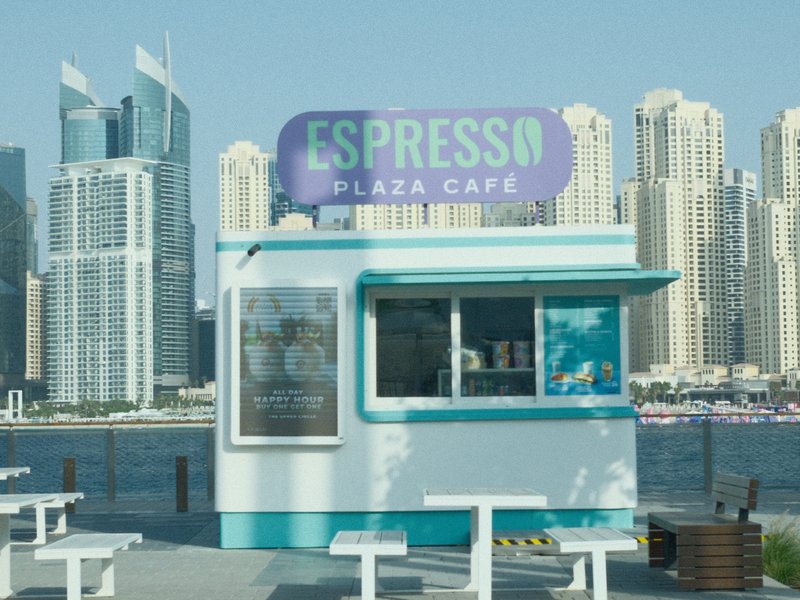 A colorful espresso cafe kiosk by the waterfront with modern skyscrapers in the background.