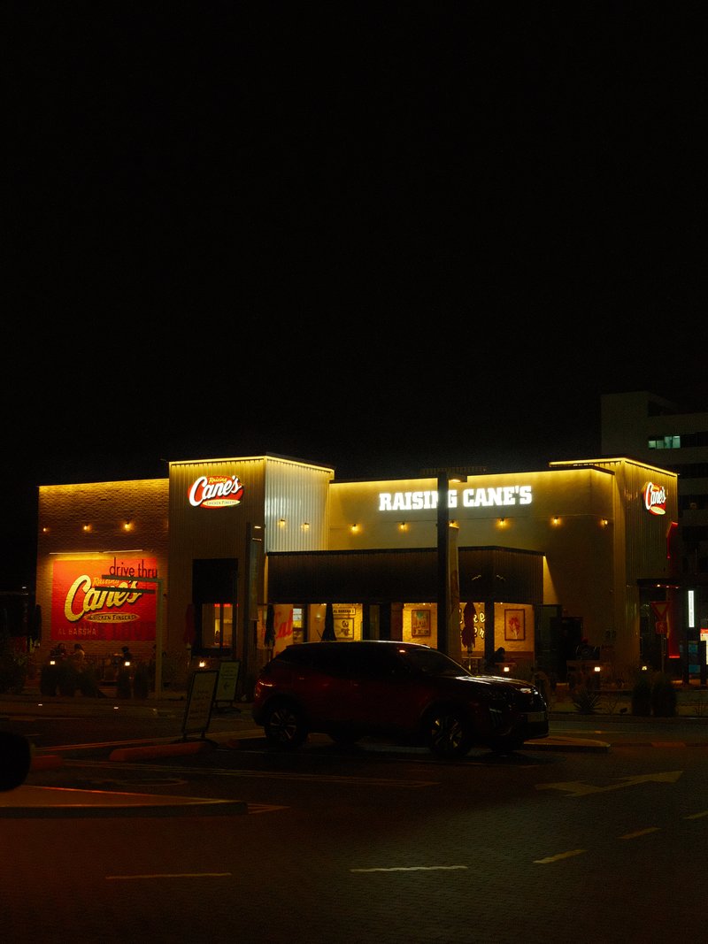 A brightly lit fast-food restaurant at night with a prominent sign and surrounding urban setting.