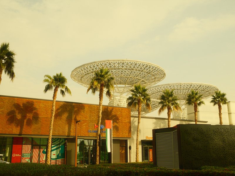 Modern architecture with palm trees under a hazy sky, featuring unique canopy structures.