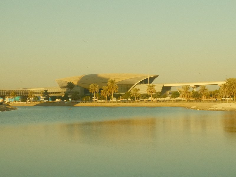 A modern architectural structure by a calm body of water during golden hour.