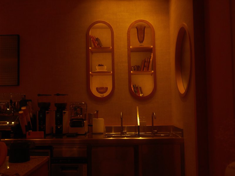 A dimly lit interior featuring shelves with decorative items and a sink area.