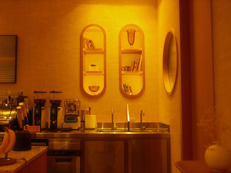 A warm-toned kitchen interior featuring shelves and a round mirror.