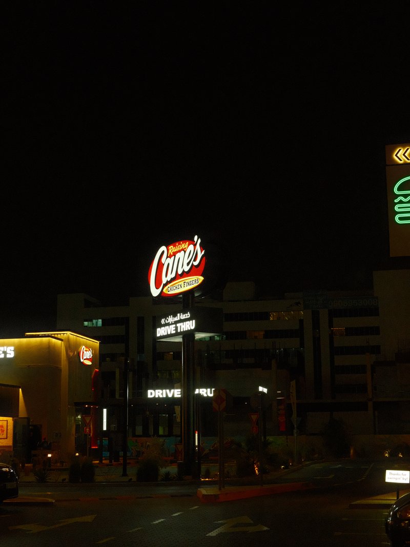 Nighttime urban scene featuring illuminated restaurant signs and buildings.