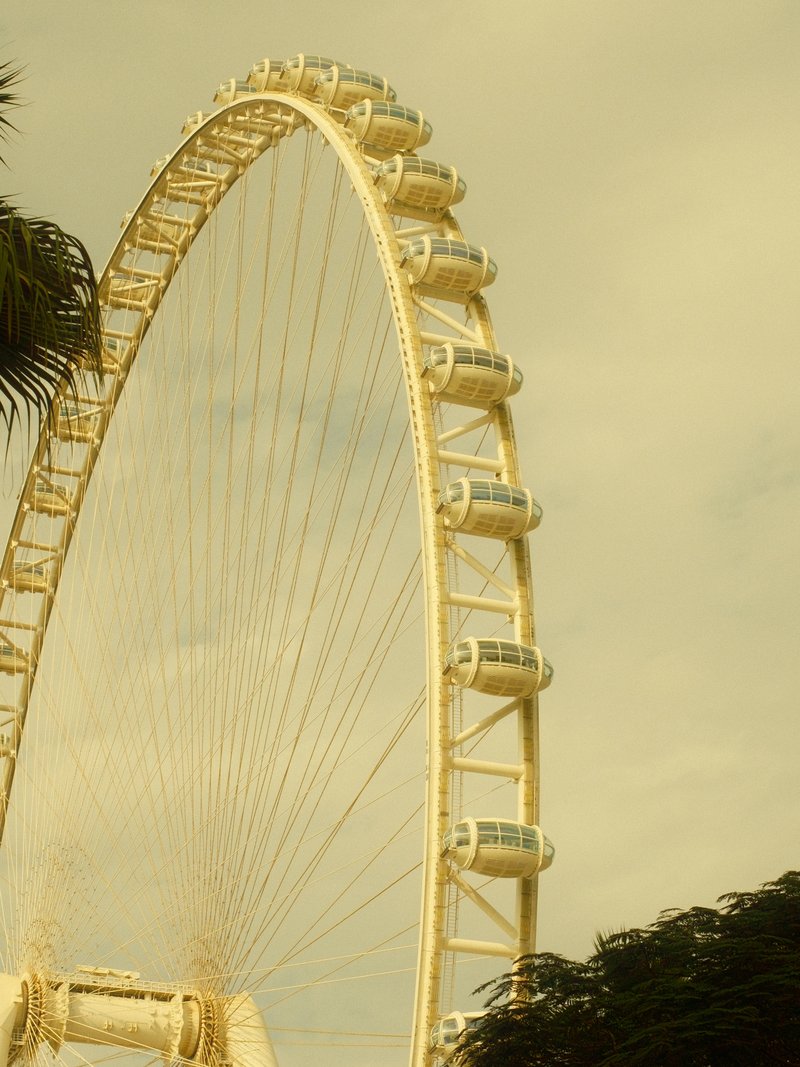 Close-up of a large ferris wheel against a cloudy sky, highlighting its structure and cabins.