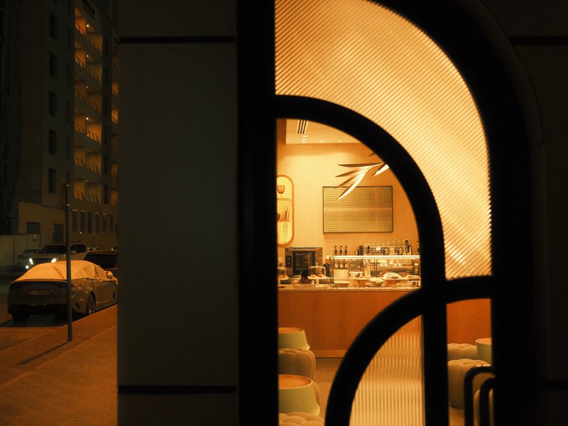 A warm-lit interior visible through an arched window at night, with a street view outside.