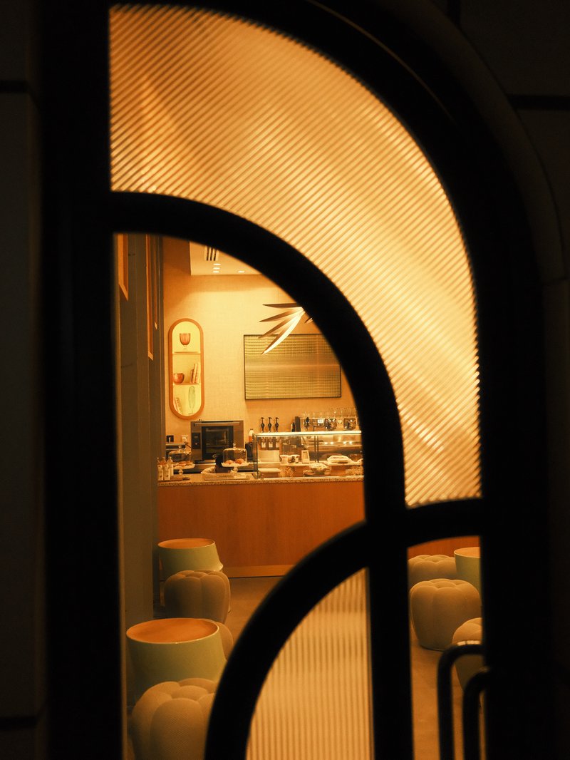 A warm-lit interior view through an arched window showcasing a cozy café setting.