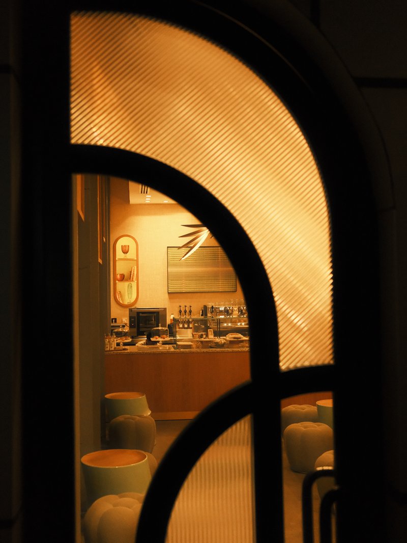 A warm, inviting interior view through an arched glass door, showcasing a cozy cafe atmosphere.