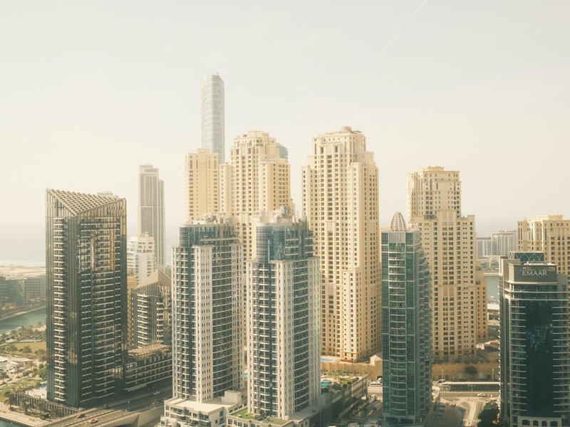 A panoramic view of modern skyscrapers in a city skyline under a hazy sky.