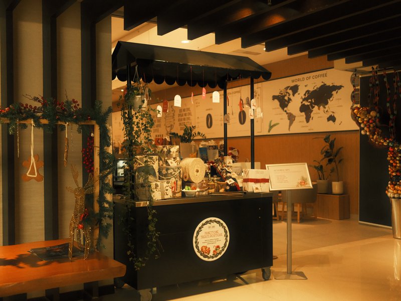 A cozy indoor market stall with a black cart, plants, and a world map on the wall.