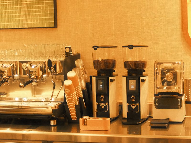A coffee station featuring espresso machines, grinders, and cups, illuminated with warm lighting.