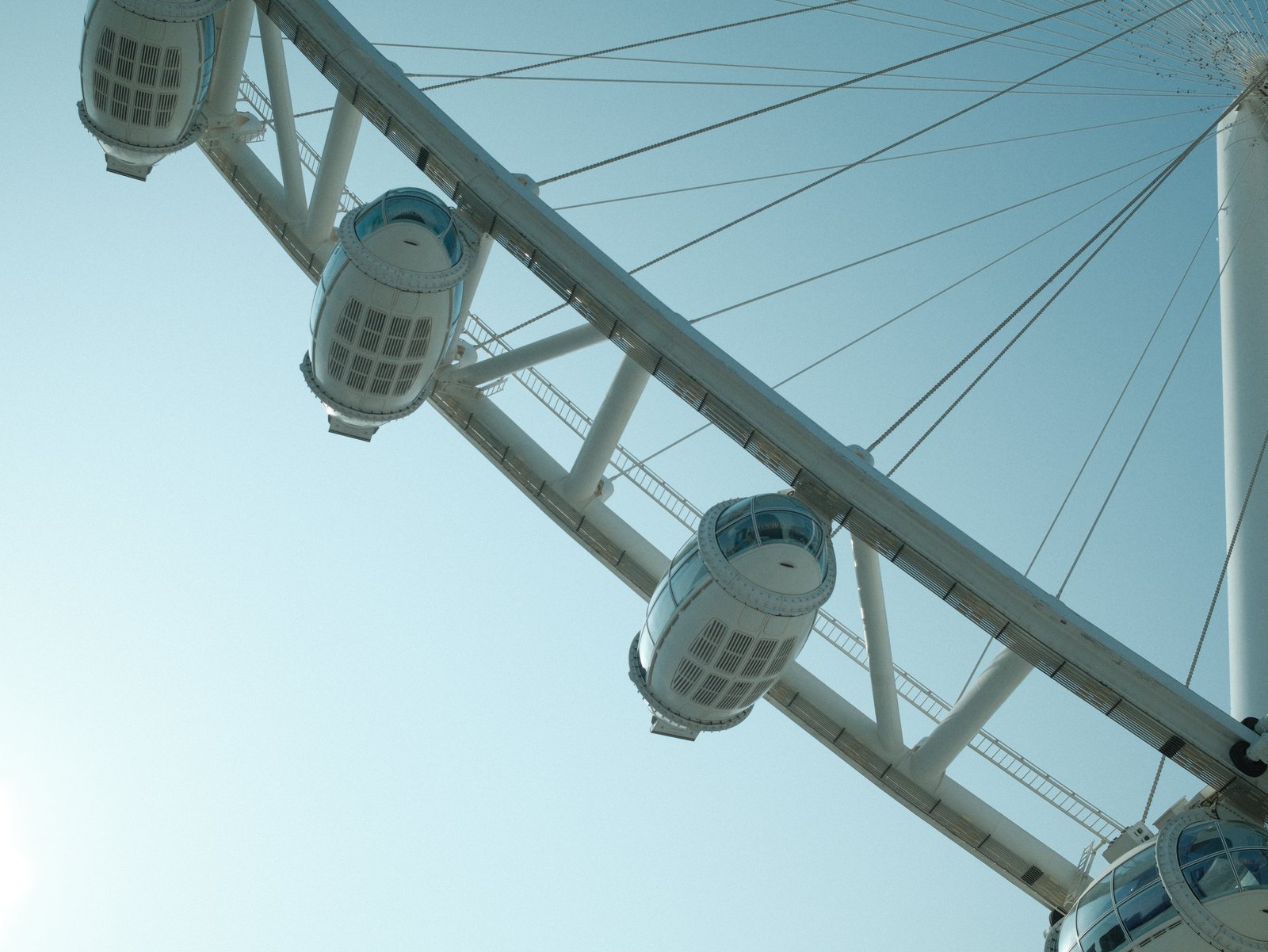Close-up view of a ferris wheel against a clear sky, showcasing the cabins and structure.