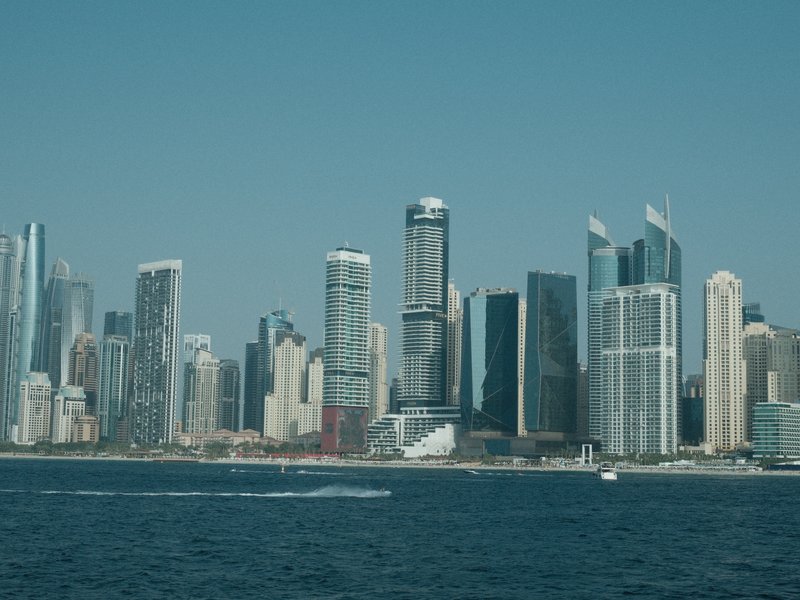 A skyline view of tall buildings along a waterfront under a clear blue sky.