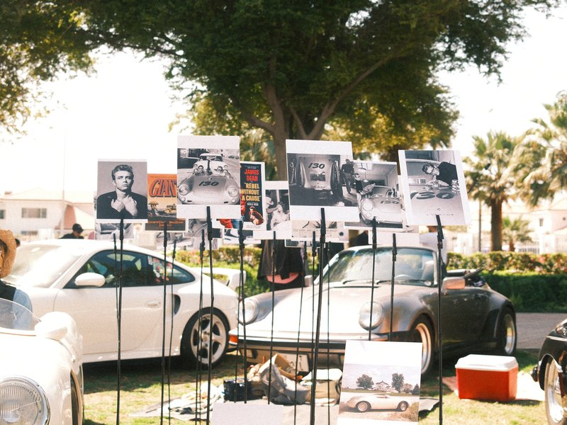 A display of black and white photographs featuring classic cars and portraits at an outdoor event.