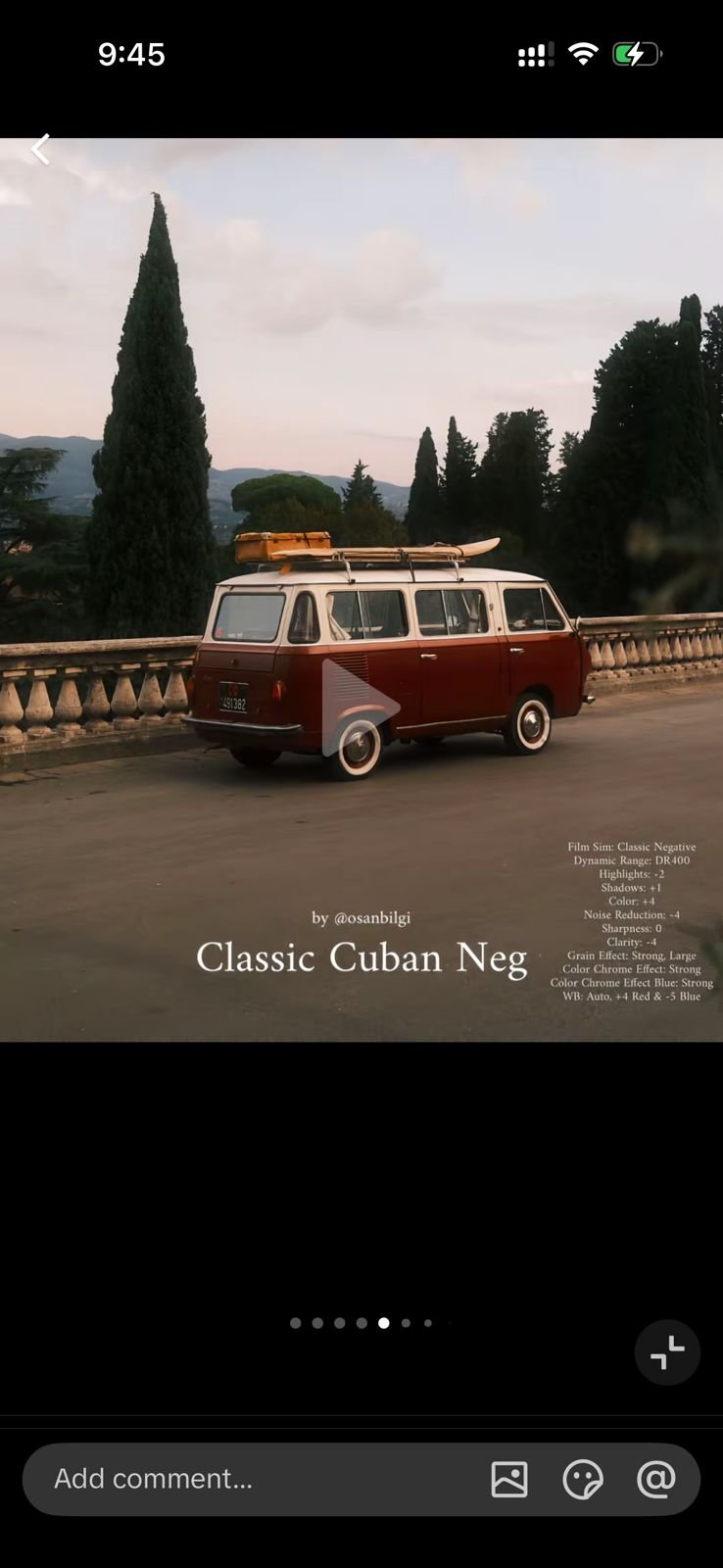 A vintage red and white van parked on a scenic road with trees and mountains in the background during golden hour.