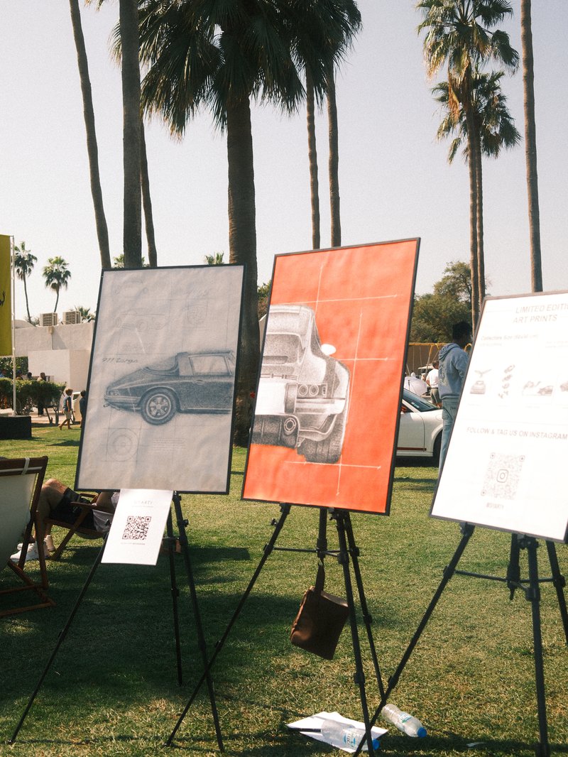 Three art pieces featuring car illustrations displayed outdoors with palm trees in the background.
