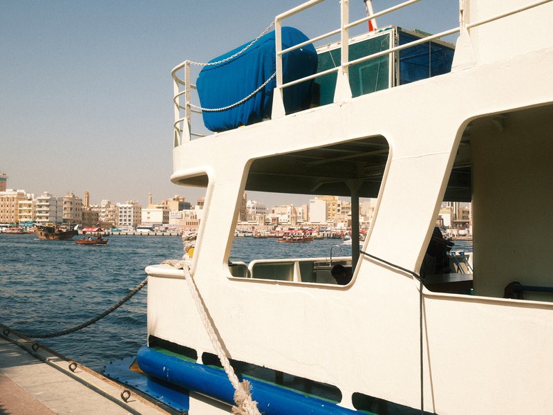 A close-up view of a boat's side with a city skyline in the background and water in the foreground.