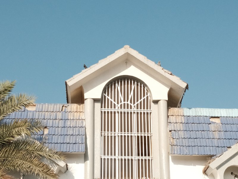 Close-up of a building's roof with decorative architecture against a clear blue sky.