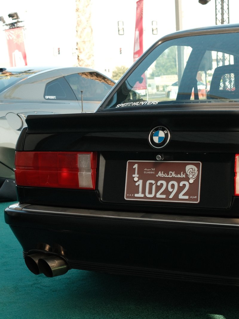 Close-up of a black BMW car's rear end with a visible license plate and exhaust pipes.