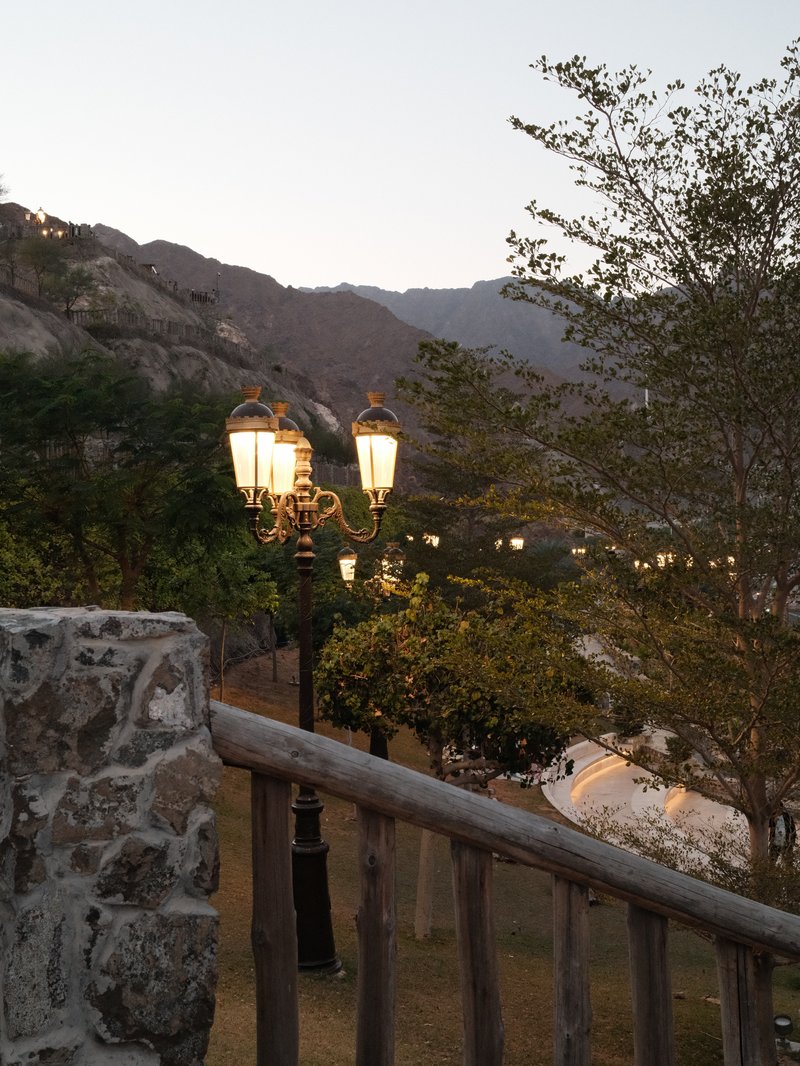 A scenic view of a lamp post with mountains in the background during twilight.