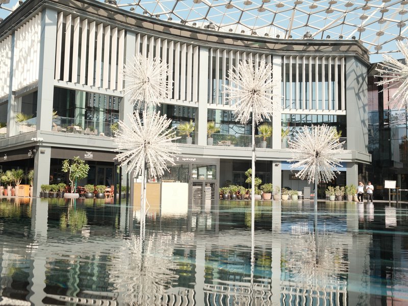 Modern architecture with reflective water surface and decorative sculptures in a bright indoor setting.