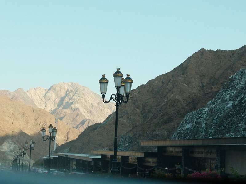 A street lamp stands in front of rocky mountains under a clear sky, creating a serene atmosphere.